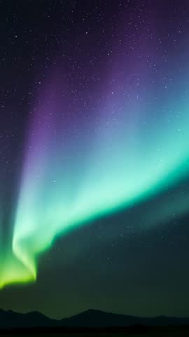 Vertical video of aurora dancing over mountains with twisting green and violet light waves