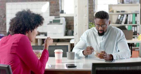 Colleagues discussing over lunch in office meeting room