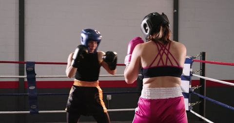 Male and Female Boxers Sparring in Gym Ring Wearing Headgear and Gloves Training