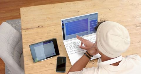 Overhead view young man working on laptop and tablet at minimalist wooden desk