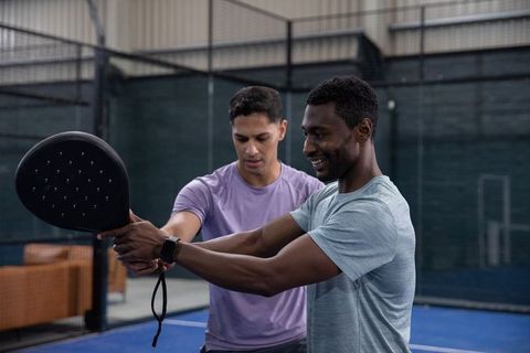 Coach guiding player through paddle grip and swing technique during indoor pickleball training