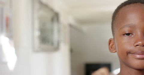 Smirking african american boy in bright hallway with soft bokeh and copy space