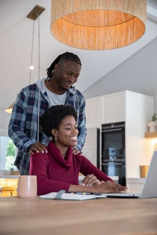 Smiling African American Couple Enjoys Shared Laptop Time in Cozy Kitchen