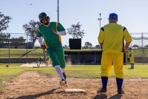 Baserunner sprinting to first base after ground ball with dust cloud and intense action