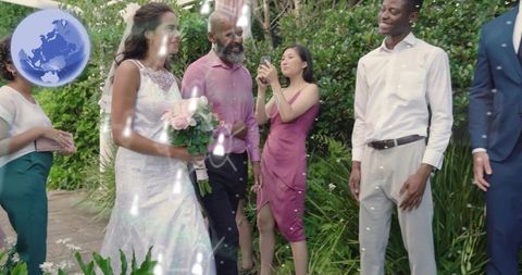 Bride walking garden pathway with attendants, veil, lace gown and pale pink rose bouquet