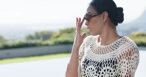 African american woman wearing tortoiseshell sunglasses and crochet top on sunny terrace