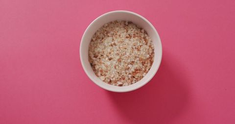 Organic salt in bowl on pink background high angle view