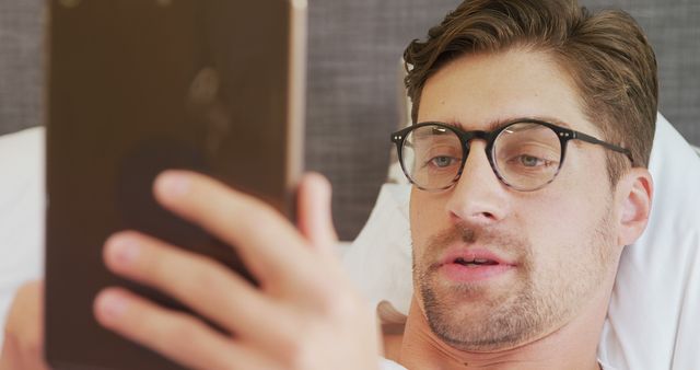 Young Man with Glasses Reading Tablet in Bed - Download Free Stock Images Pikwizard.com