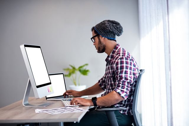 Serious hipster working at computer desk in office