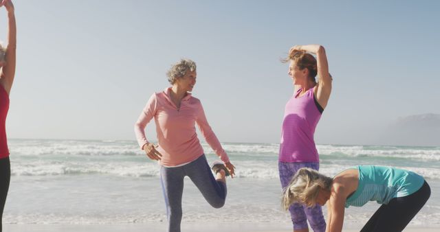 Diverse women wearing sports clothes and stretching at beach. Sport, friendship, healthy and active lifestyle.