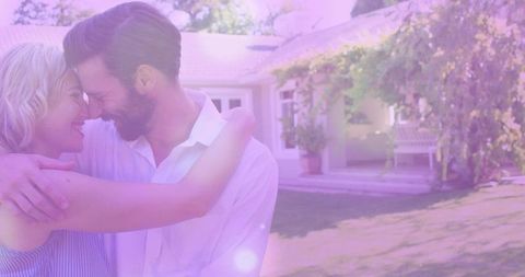 Couple embracing, touching foreheads on sunny suburban lawn