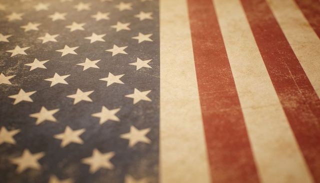 Worn vintage american flag close-up showing distressed stars and stripes, textured patina