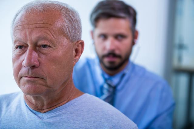 Senior man being examined by a doctor using a stethoscope. Ideal for healthcare, medical services, elderly care, and patient-doctor relationship themes. Useful for articles, brochures, and websites related to medical check-ups, senior health, and hospital services.