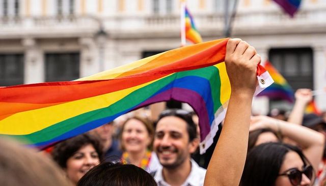 Waving rainbow pride flag over smiling crowd celebrating lgbtq+ unity at urban pride parade