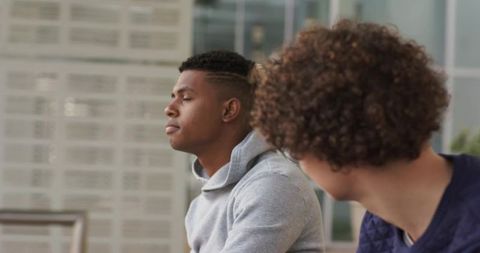 Young Man Reflecting While Friend Conversing on Urban Bench — Candid Friendship Moment