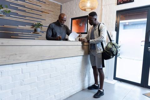 African american gym staff assisting client signing membership forms at modern reception