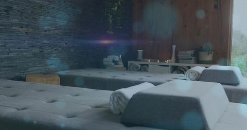 Serene spa lounge featuring tufted grey daybeds with rolled towels and soft candlelight