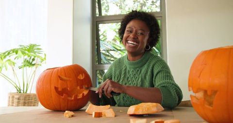 Joyful Woman Carving Pumpkins for Halloween Celebration