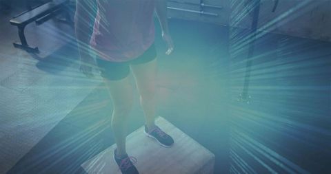 Woman balancing on plyometric box in gym with neon light focused fitness training for stability