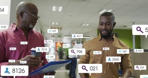 Colleagues discussing analytics overlays in modern open-plan office holding coffee