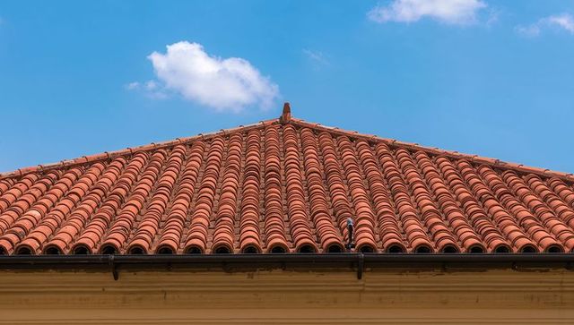 Terracotta barrel-tiled pitched roof featuring symmetrical clay tiles, ridge detail and gutter under