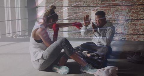 Female boxer training with coach in ring