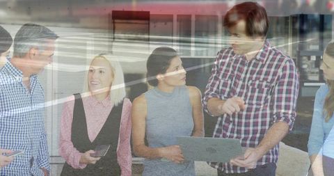 Business team collaborating around laptop with glass reflections and mobile devices