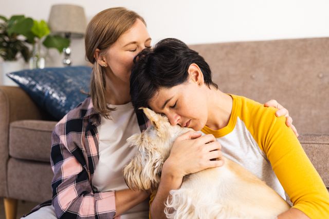 This image depicts a loving lesbian couple sharing an intimate moment at home while embracing their Scottish terrier. Ideal for use in articles or advertisements focusing on LGBTQ relationships, pet care, domestic life, and family bonds. Perfect for promoting inclusivity, love, and togetherness in various lifestyle and home-related contexts.