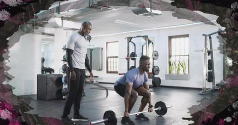 Male trainee performing barbell deadlift under coach supervision in modern gym interior