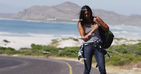 Woman adjusting backpack on coastal roadside