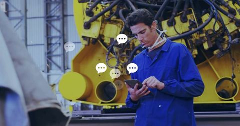 Technician checking tablet beside yellow hydraulic machinery, wearing coverall and mask