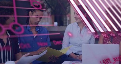 Team collaborating over documents and laptop with pink glass notes in modern workspace