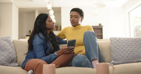 Diverse Friends Bonding Over Smartphone in Cozy Living Room
