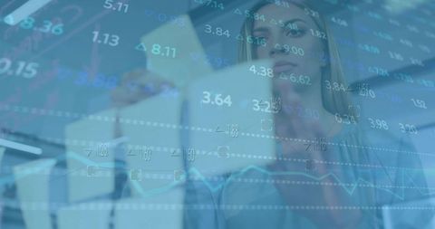 Businesswoman analyzing financial data with translucent digital charts overlaying office