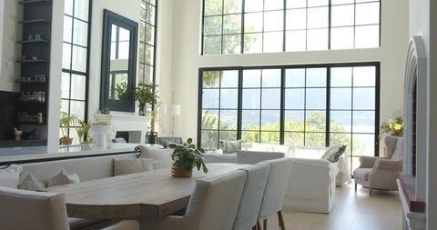 Sunlit farmhouse dining room with rustic wooden table and oversized grid windows