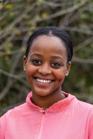 Confident african american woman smiling in pink athletic top outdoors