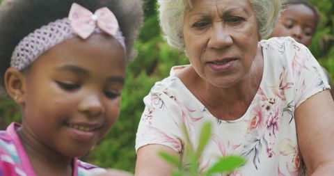 Happy Grandmother and Granddaughters Gardening Together Outdoors