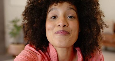 African american woman leaning toward camera smiling warmly in cozy living room portrait
