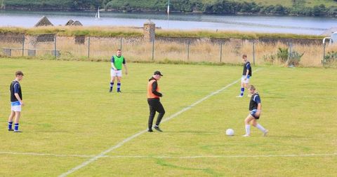 Teenage Soccer Team Training with Coach on Green Field
