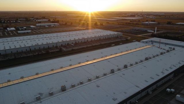 Sunrise reflecting on flat-roof warehouses with rooftop hvac, skylights and logistics trailers