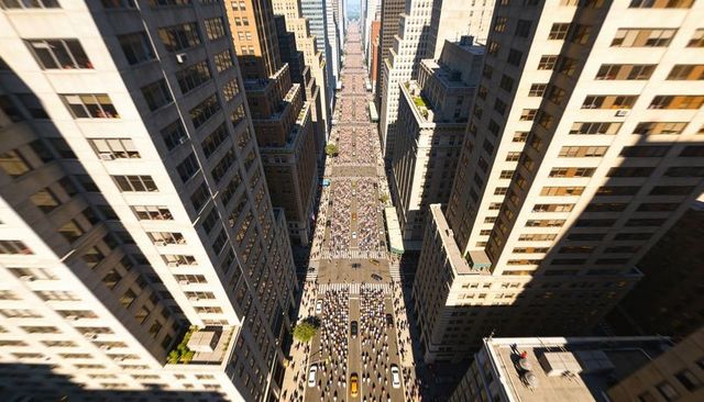Sunlit midtown avenue teeming with commuters, yellow taxi and downtown rush hour crowd