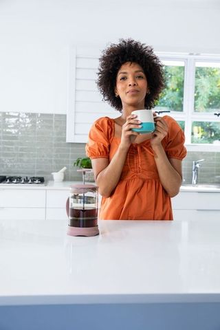 Relaxed Woman Enjoying Coffee in Modern Kitchen with French Press