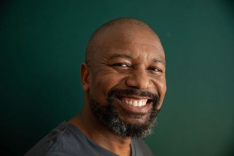 Warm smiling mature african american man with salt-and-pepper beard on green background