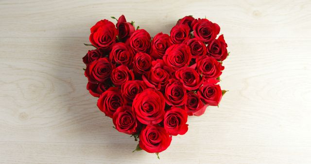 This heart-shaped arrangement of red roses on a wooden background is perfect for celebrating love and special occasions. Use it for Valentine's Day promotions, wedding decor, romantic gestures, anniversary greetings, or floral shop advertisements.