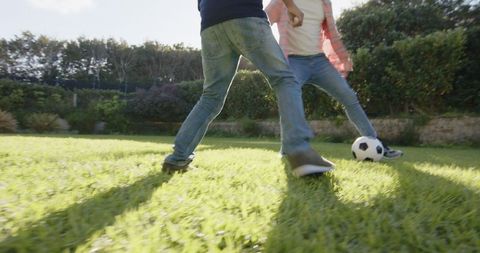 Father and son enjoying soccer in backyard on sunny afternoon