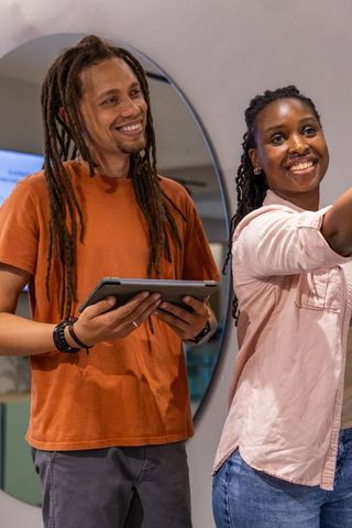 Smiling african american colleagues collaborating with tablet and circular mirror