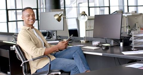 Businessman Sitting at Desk Using Tablet in Modern Office