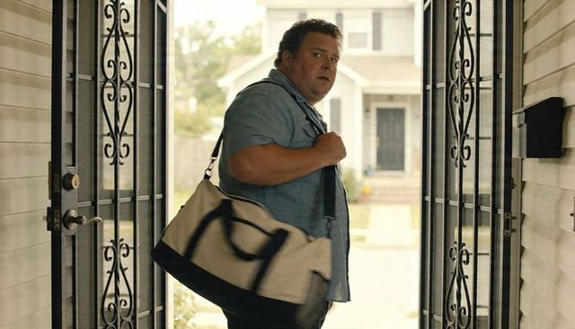 Man leaving home looking back over shoulder while carrying duffel bag
