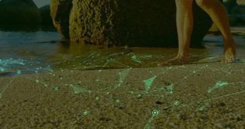 Barefoot man wading on pebble beach with futuristic green holographic mesh overlay