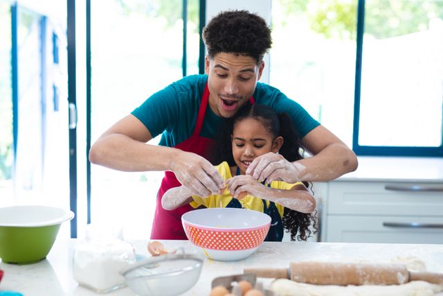 Father teaching daughter to break an egg in a kitchen. Great for illustrating family bonding, cooking lessons, parenting, and home activities. Suitable for use in articles, blogs, and advertisements about family life, cooking, and education.